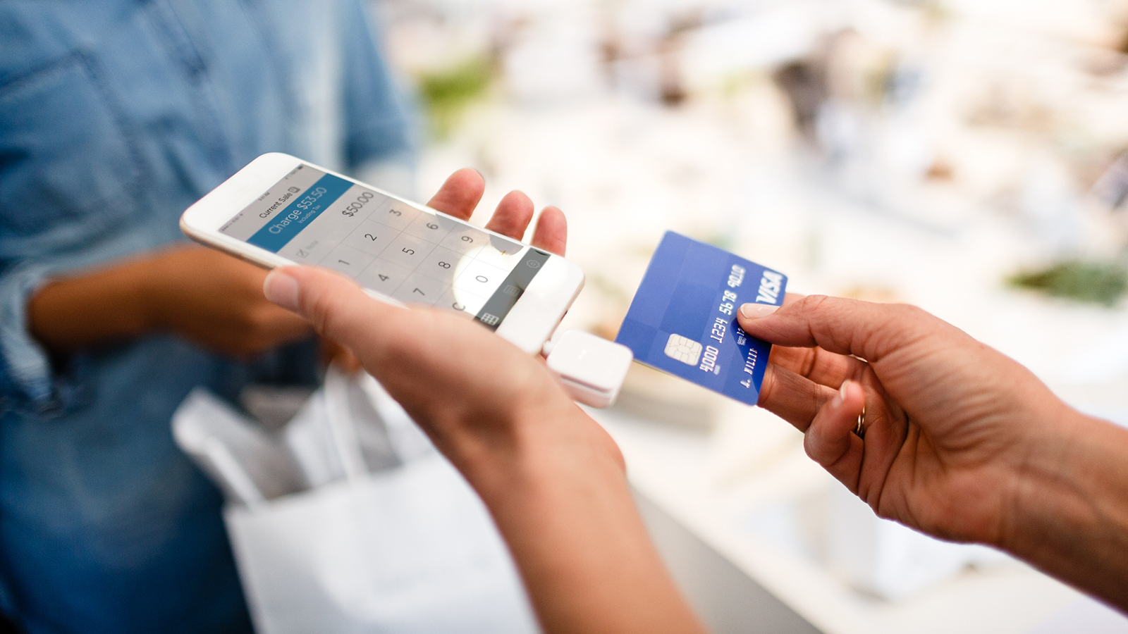 Mujer usando su telefono para completar transaccion Merchant using a mobile phone to complete a transaction