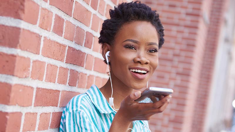 smiling-woman-with-earphones-on-phone-800x450