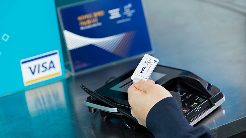 An Olympic participant promoting Visa winter wearables sticker with pin by checking out at a store with the pin enabled sticker.