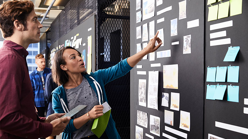 Man and woman discussing an item on a Scrum Task Board. Man and woman discussing an item on a Scrum Task Board.