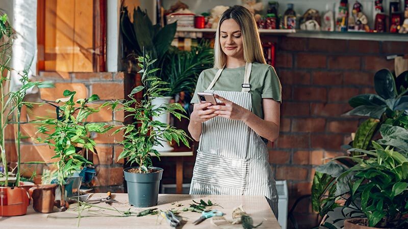 Gardener using her cell phone at her workplace