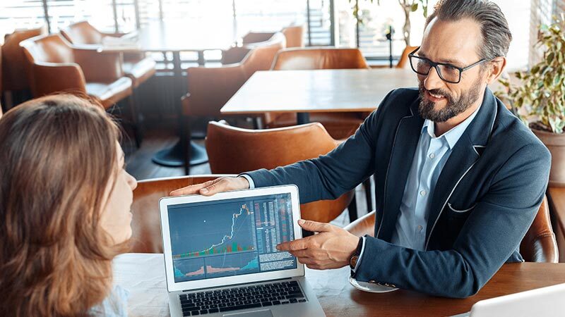 business man showing charts on computer to woman