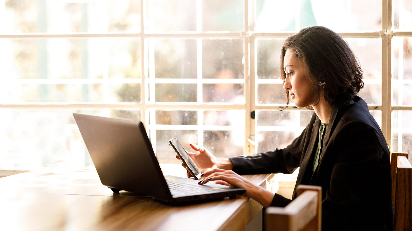 Mujer utilizando teléfono móvil y laptop