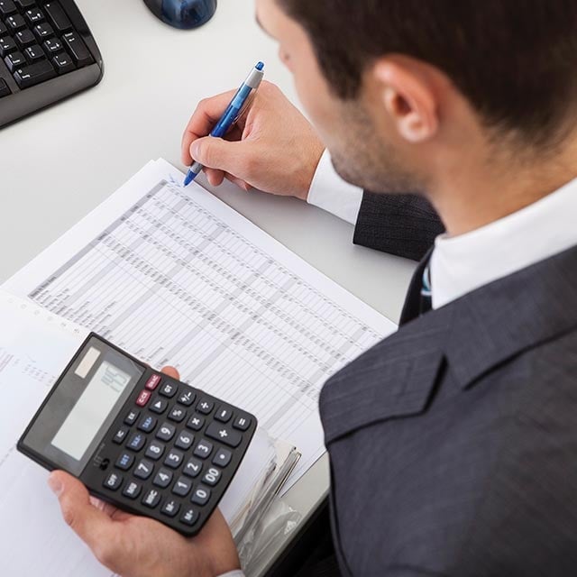 Hombre de traje revisando registros con su calculadora