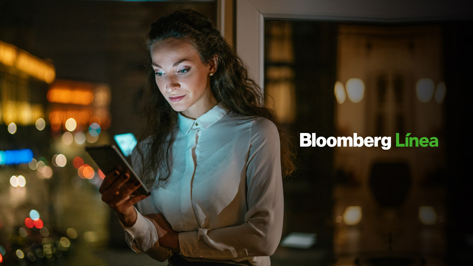 Mujer usando su celular con logo Bloomberg Línea