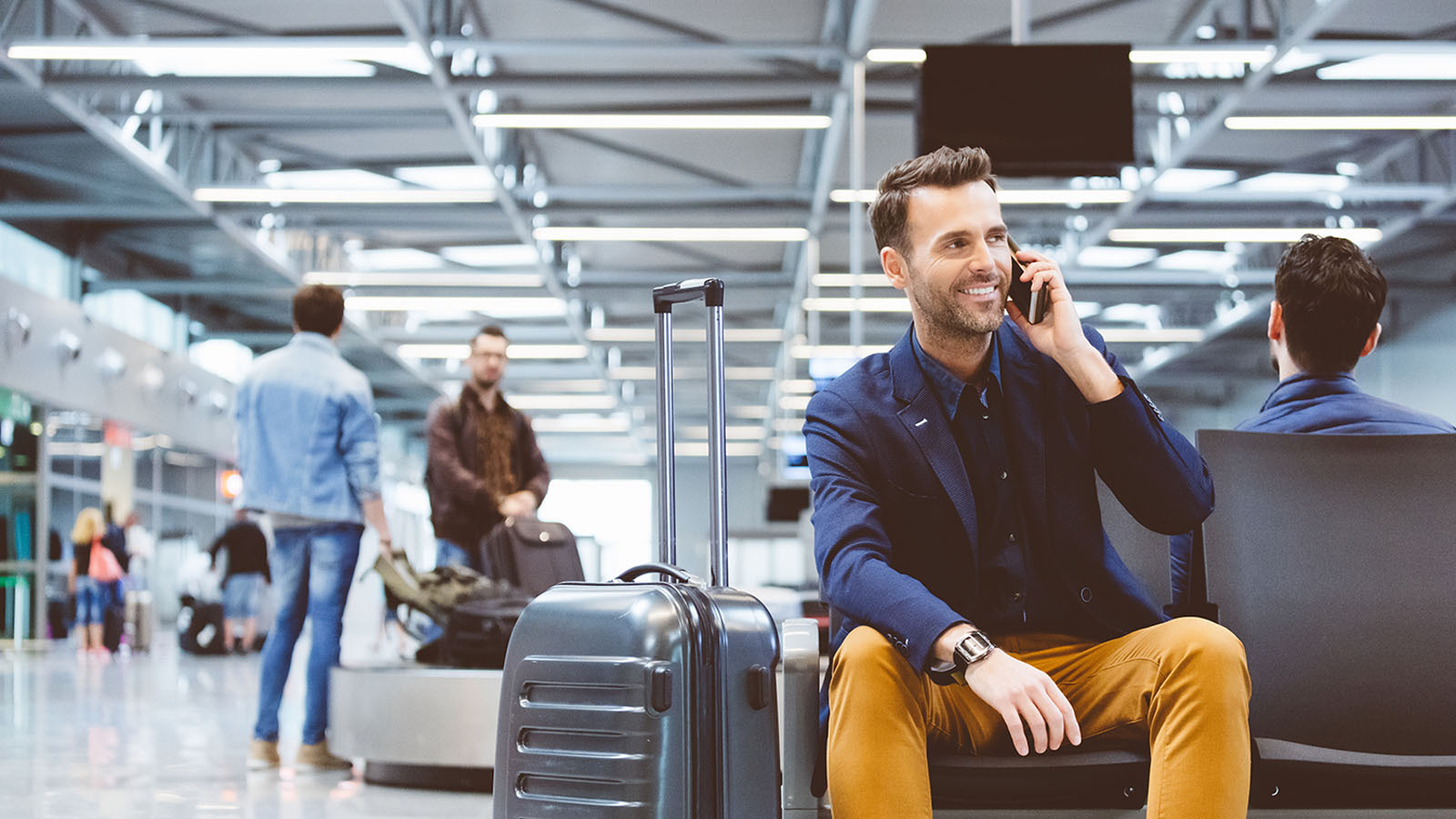 Hombre sonriente hablando por teléfono en un aeropuerto