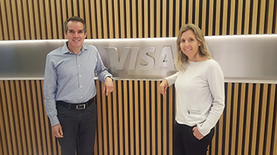 Hombre y mujer posando al lado del logo de Visa