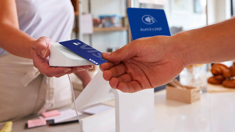 Persona haciendo un pago contactless con tarjeta Visa en un comercio