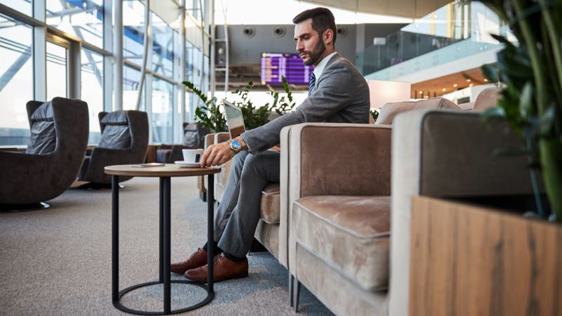 visa-infinite-lounge-e-visa-infinite-fast-pass imagem exibe homem sentado tomando café em sala vip de aeroporto.